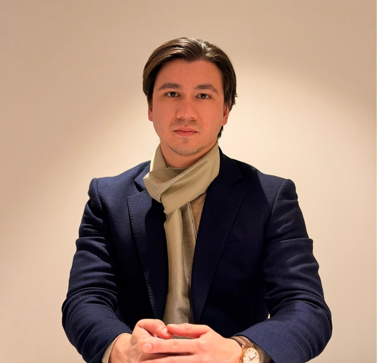 Bruno Klarenbeek Foto van Bruno Klarenbeek zittend aan een tafel met een sjaal en pak